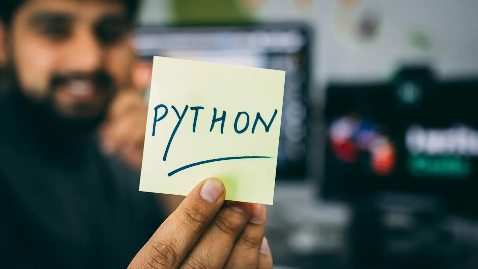 Developer holding a sticky note that reads Python
